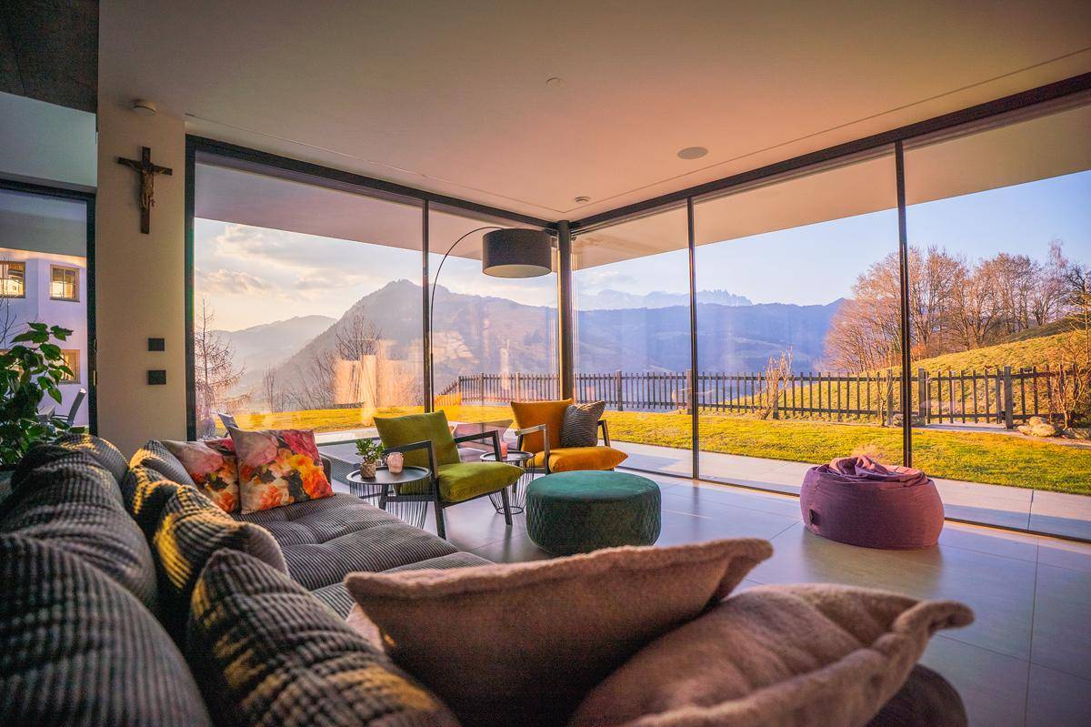 Lichtdurchflutetes Wohnzimmer mit bodentiefen Fenstern, die einen atemberaubenden Bergblick freigeben.