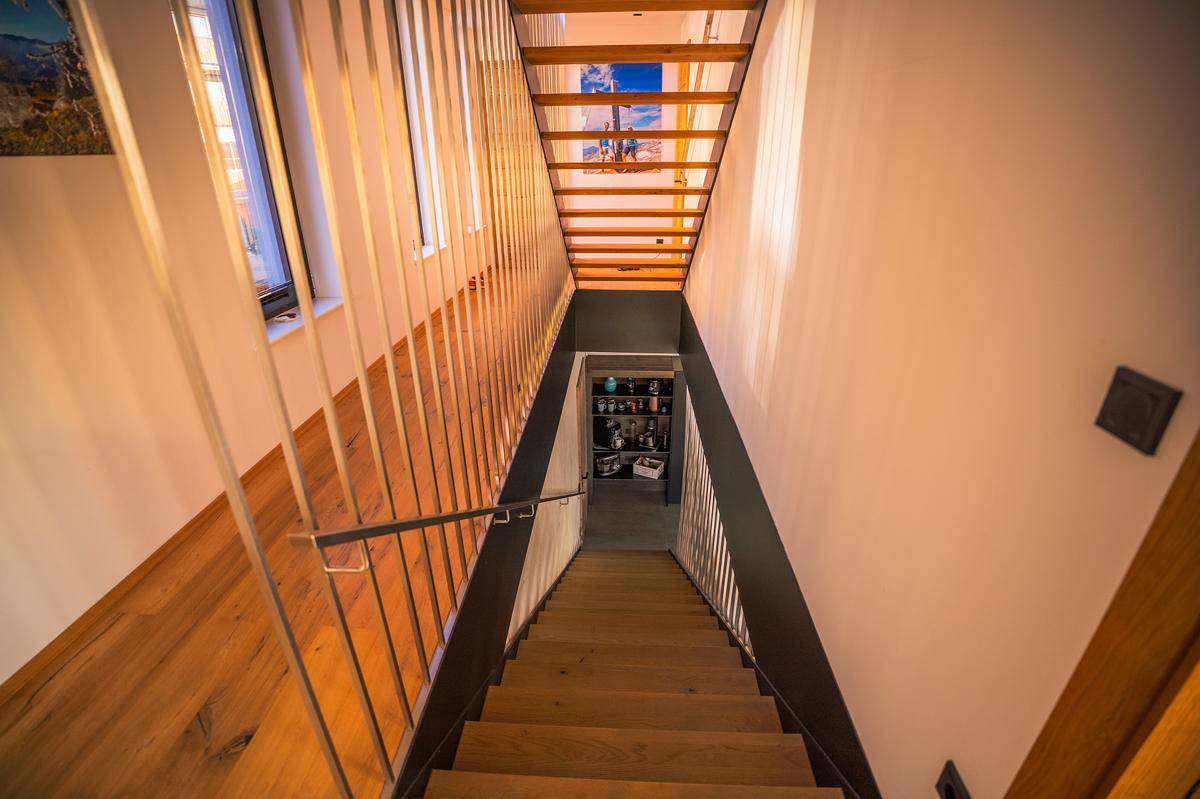Moderne Holztreppe mit schlankem Metallgeländer, die die verschiedenen Wohnebenen stilvoll verbindet.
