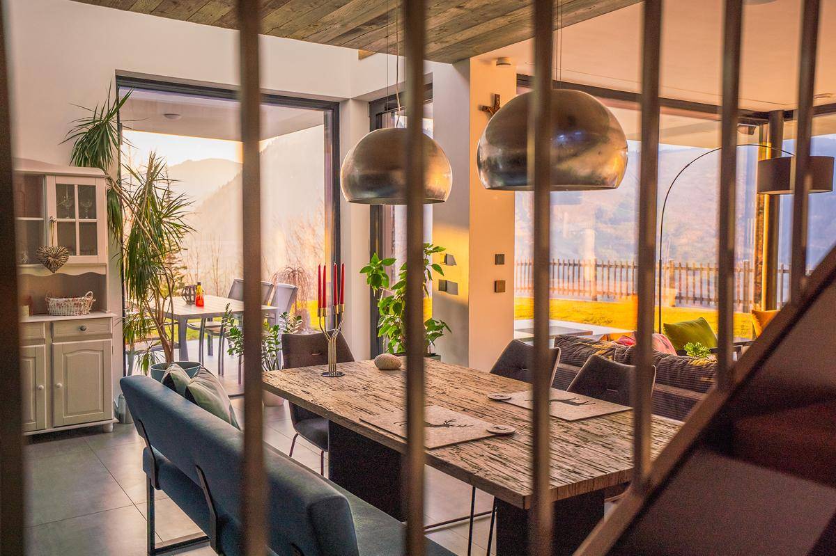 Eleganter Essbereich mit rustikalem Holztisch, modernen Pendelleuchten und Blick auf die Terrasse.