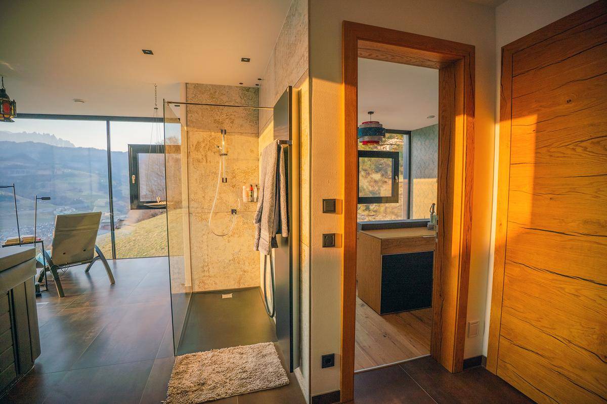 Modernes Badezimmer mit begehbarer Dusche, großen Fenstern und beeindruckendem Bergblick.