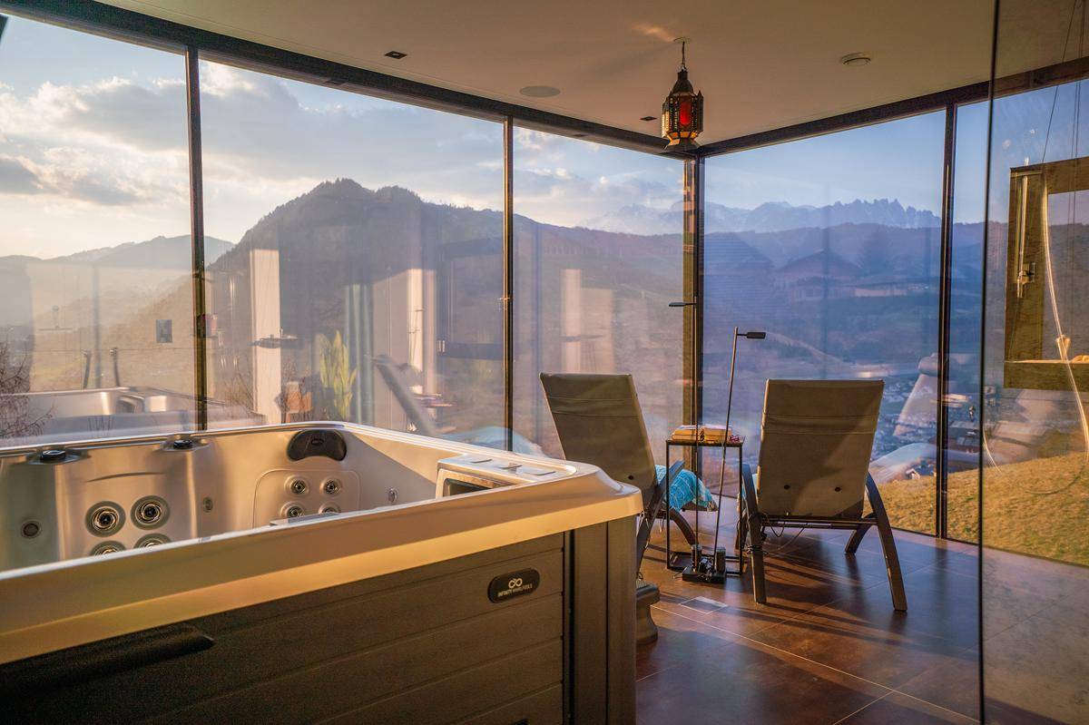 Exklusiver Wellnessbereich mit Whirlpool und Panoramafenstern, die einen weiten Bergblick bieten.
