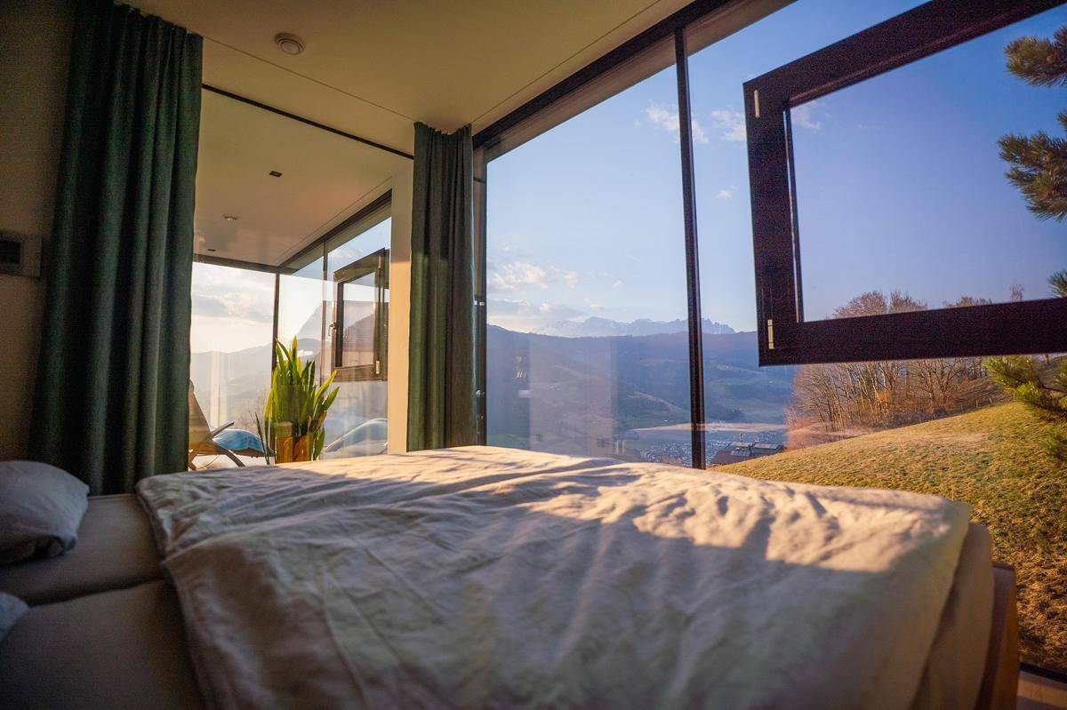 Helles Schlafzimmer mit bodentiefen Fenstern, die einen weiten und ungestörten Bergblick ermöglichen.