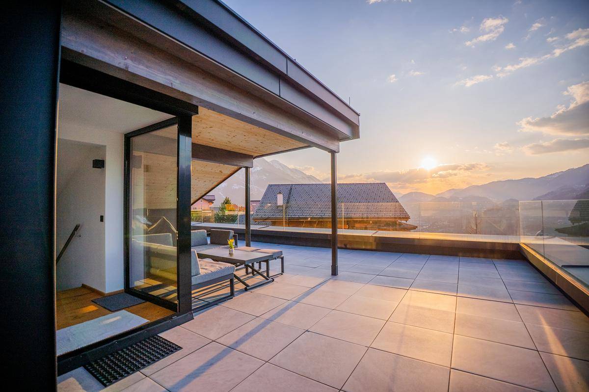 Großzügige Dachterrasse mit bequemen Lounge-Möbeln und einem weiten Panoramablick auf die Berge.