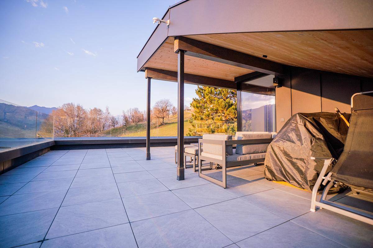 Überdachte Dachterrasse mit Sitzgelegenheiten, ideal für Entspannung und Genuss der Landschaft.
