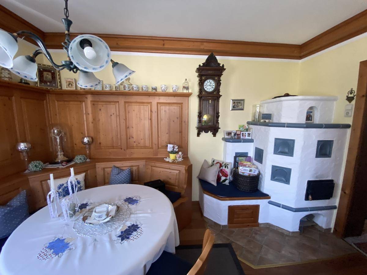 Gemütlicher Essbereich mit traditionellem Kachelofen, Holztäfelung und rustikalem Charme.