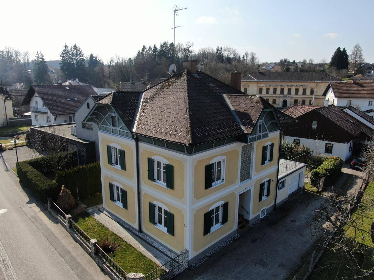 Luftaufnahme des gelben Hauses mit markanter Dachform und umliegender Wohnbebauung.