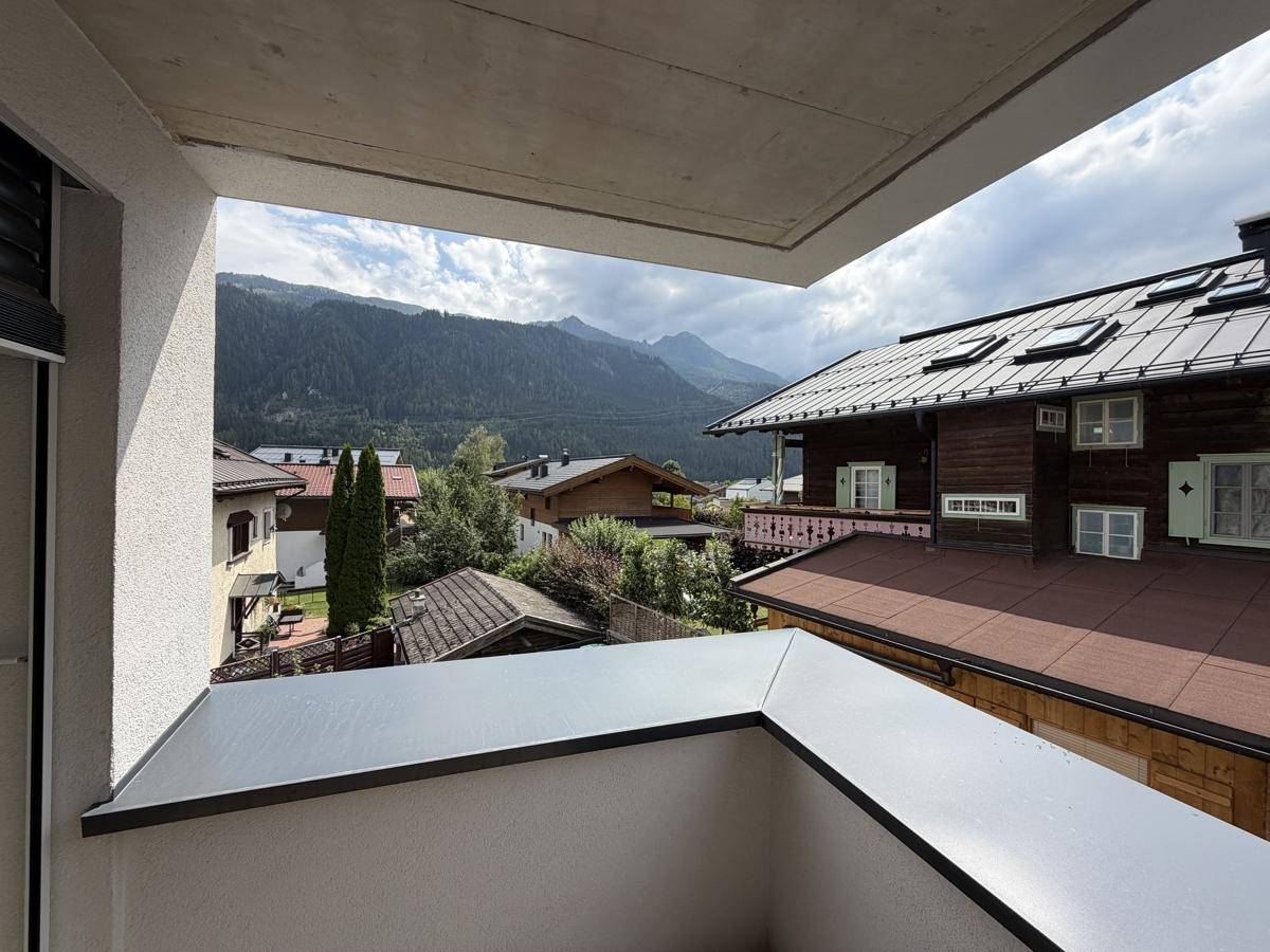 Blick vom Balkon auf die umliegende Berglandschaft und traditionelle Häuser.
