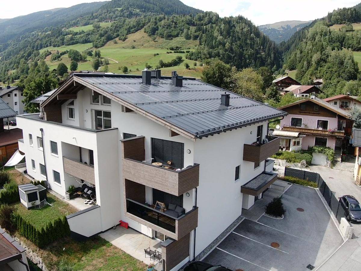 Moderne Wohnanlage mit Balkonen und Parkplätzen vor einer Bergkulisse.