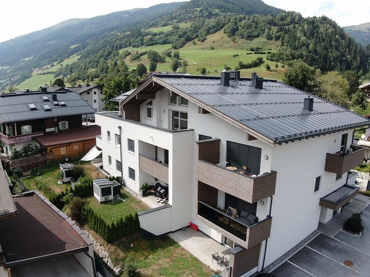 Neubau-Wohngebäude mit Balkonen und gepflegter Grünfläche in den Bergen.