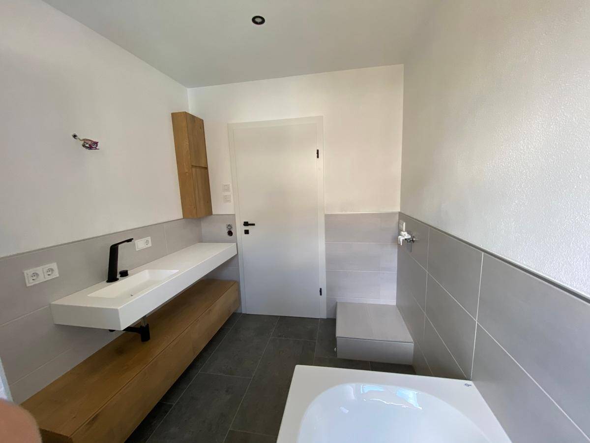 Modernes Badezimmer mit schwebendem Waschtisch, Wand-WC und Badewanne.