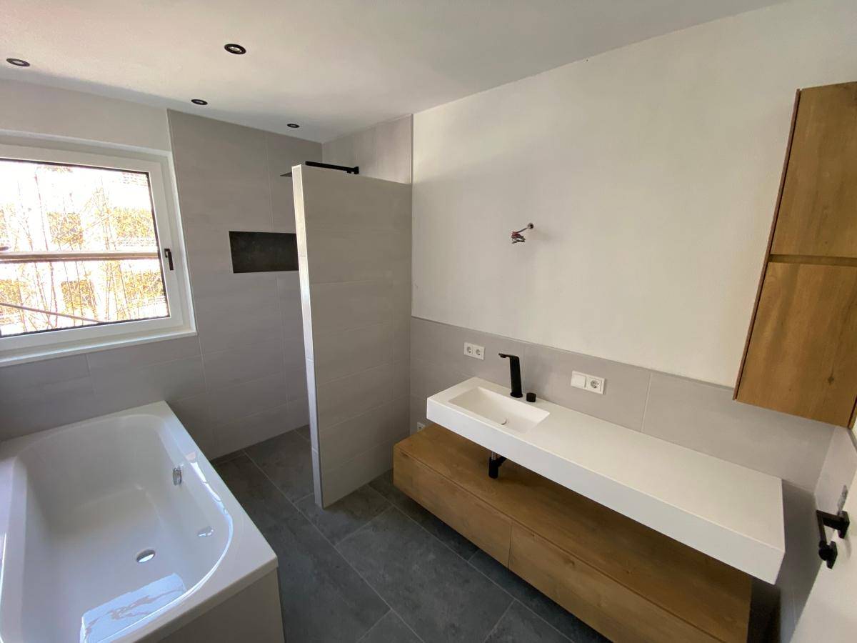 Modernes Badezimmer mit Badewanne, begehbarer Dusche und stilvollem Holzwaschtisch.