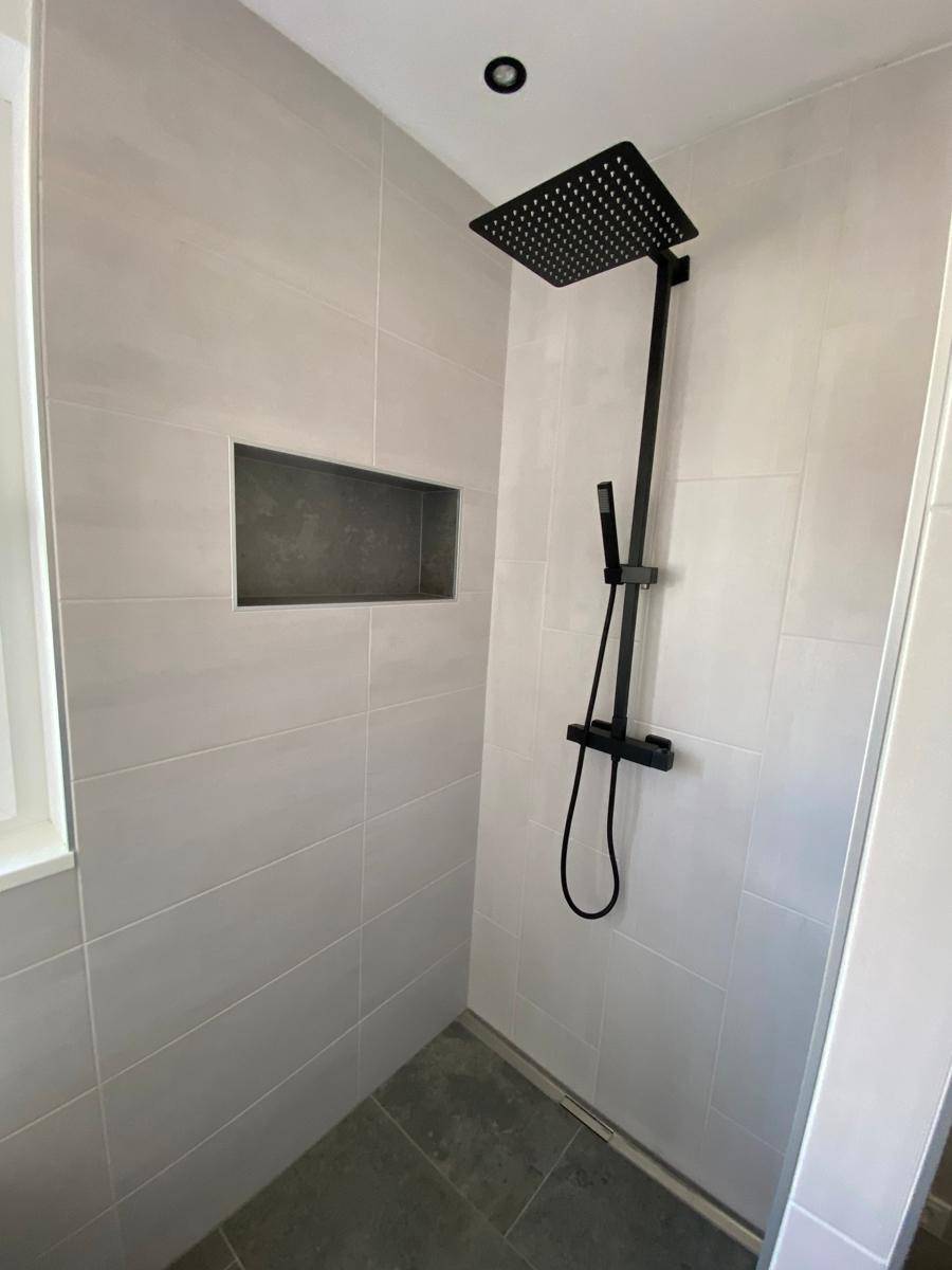Begehbare Dusche mit moderner schwarzer Regendusche und eleganten grauen Fliesen.