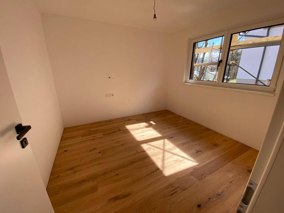 Helles Schlafzimmer mit Holzboden und viel Tageslicht durch das Fenster.