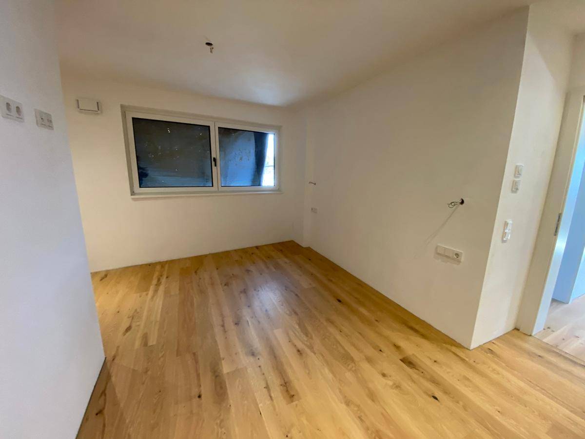 Unmöbliertes Zimmer mit Holzboden und Fenster, ideal als Schlaf- oder Arbeitszimmer.