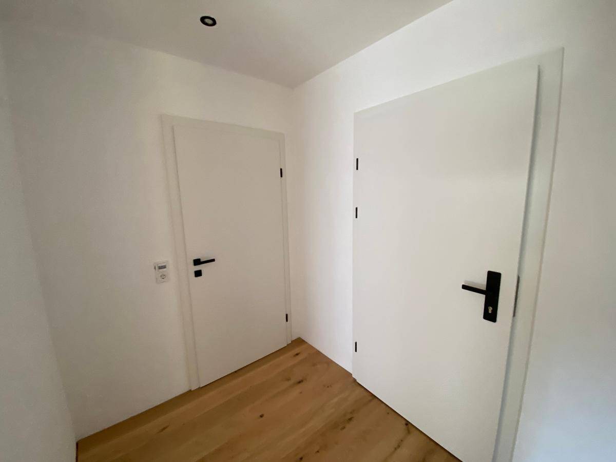 Heller Flur mit zwei weißen Türen und warmem Holzboden.