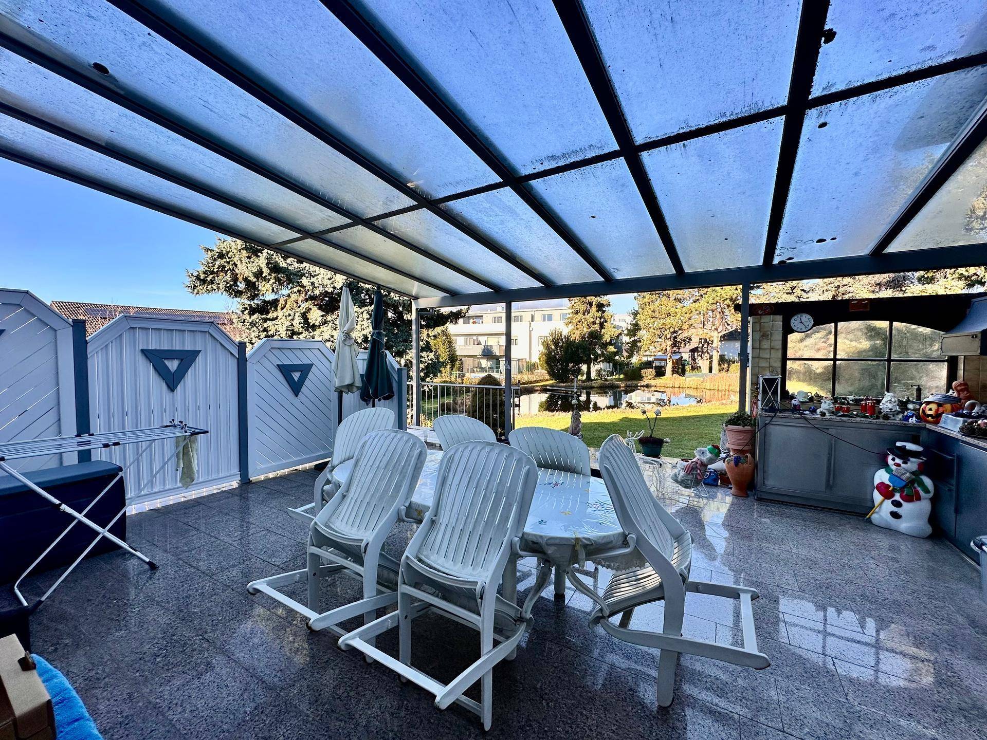 Überdachte Terrasse mit Esstisch und Stühlen, ideal für Mahlzeiten im Freien mit Gartenblick.