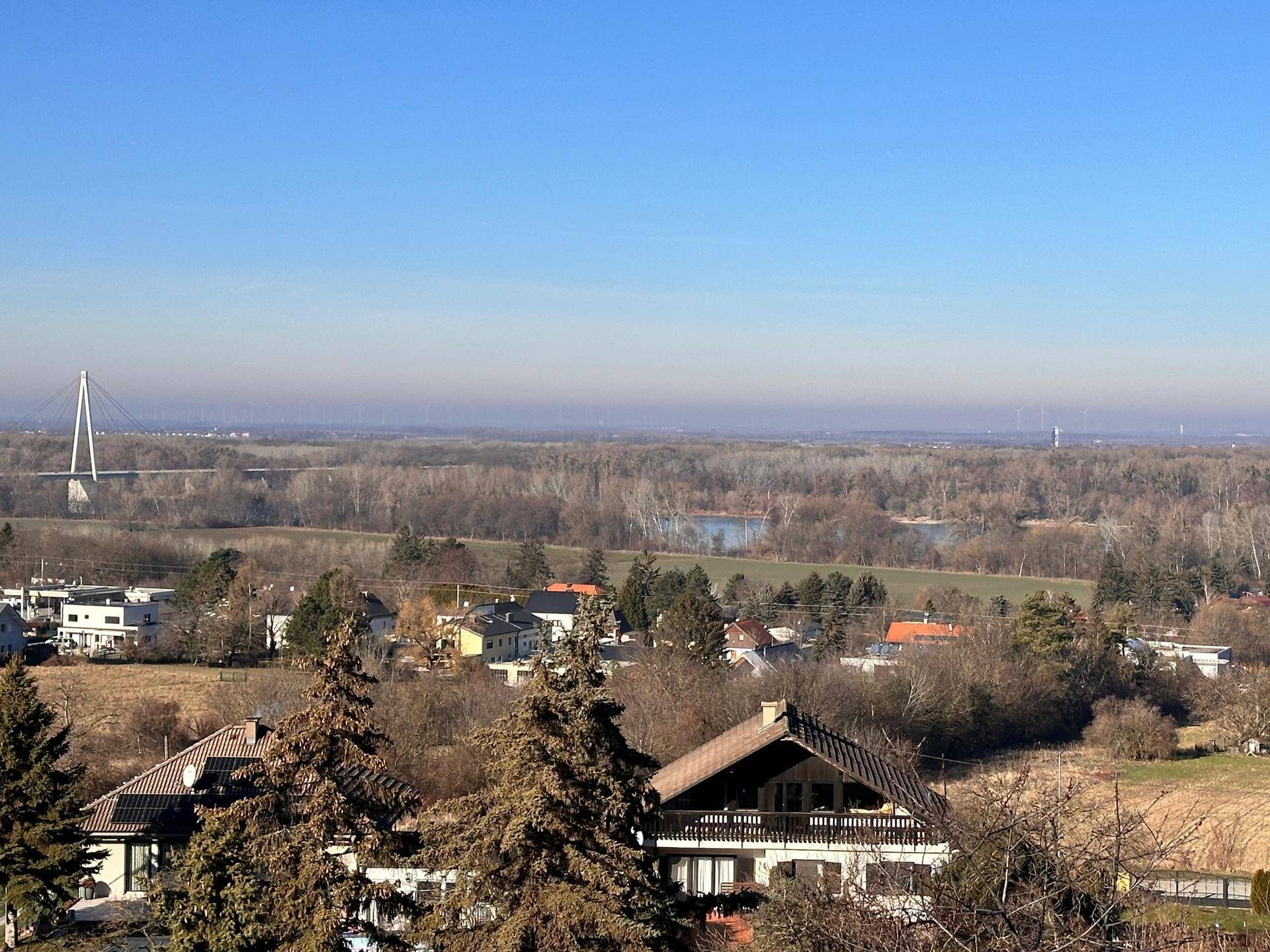 Weitläufiger Blick über die Landschaft mit Fluss, Brücke und umliegenden Häusern.