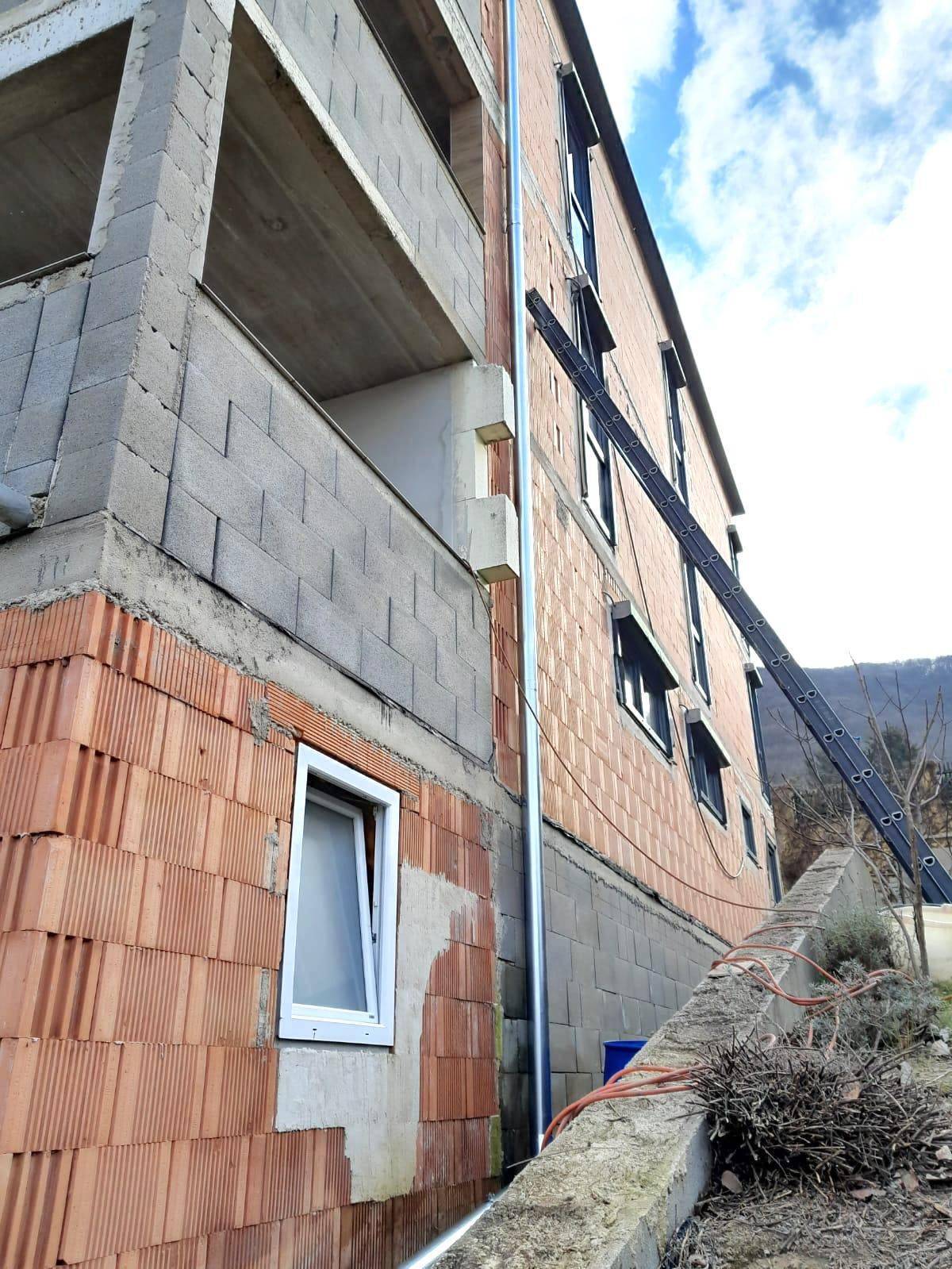 Fassade eines im Bau befindlichen Gebäudes mit Ziegeln und Betonstrukturen.