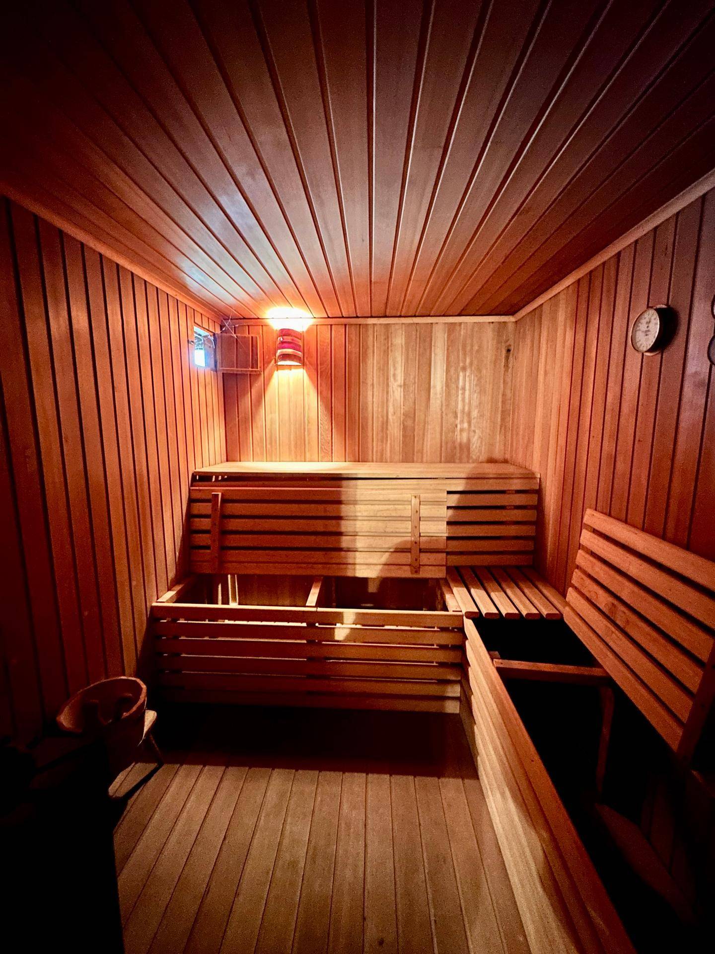 Gemütliche Holzsauna mit Bänken und stimmungsvoller Beleuchtung für Entspannung.