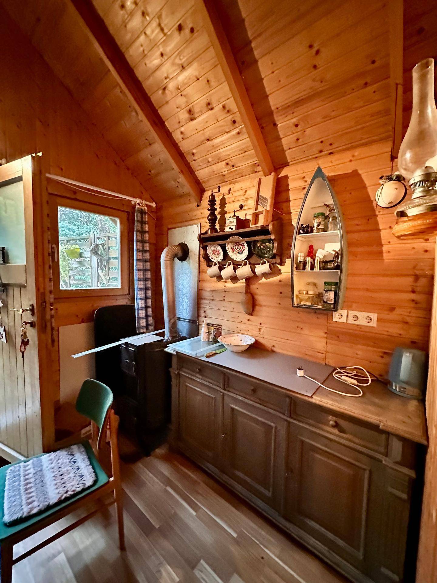 Kleine, funktionale Küche in einer Holzhütte mit Holzvertäfelung und traditionellem Ofen.
