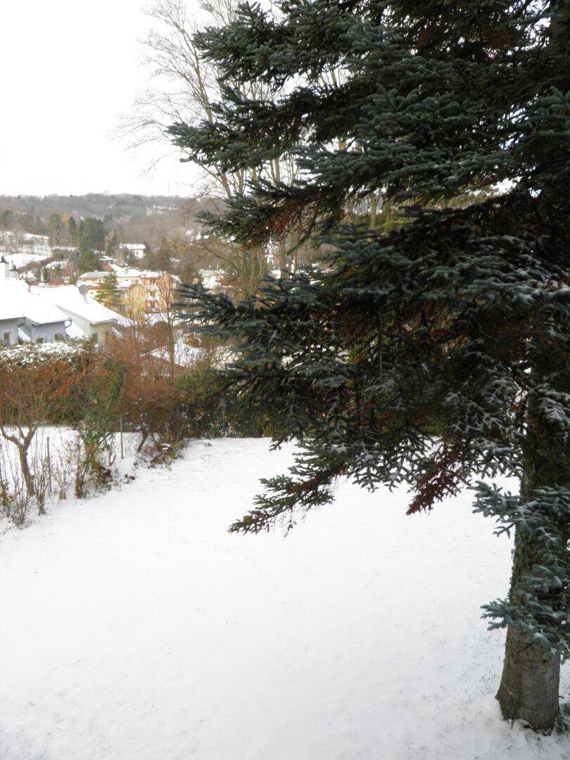 Winterlicher Gartenbereich mit Schnee und einem weiten Blick auf die Umgebung.