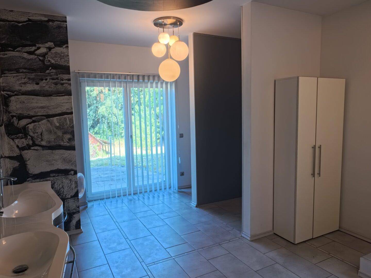 Helles Badezimmer mit Schiebetür zum Garten, Doppelwaschbecken und modernem Design.