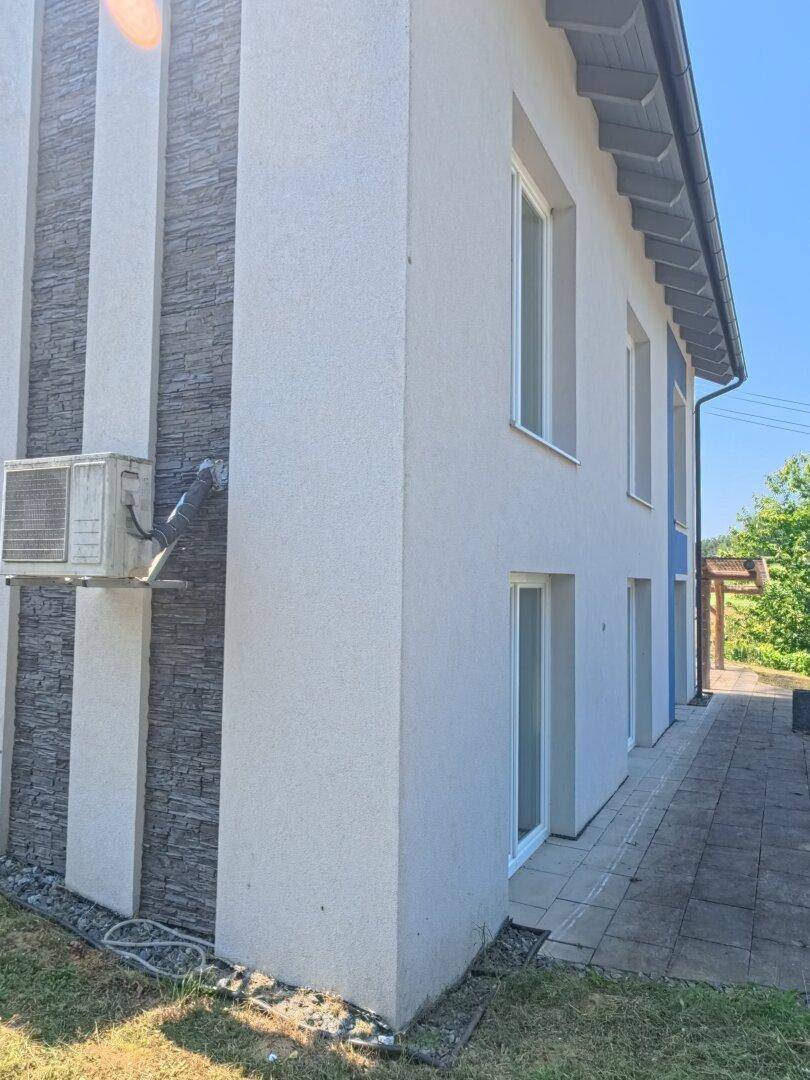 Detailansicht der Hausfassade mit Klimaanlage und modernem blauen Akzentstreifen.