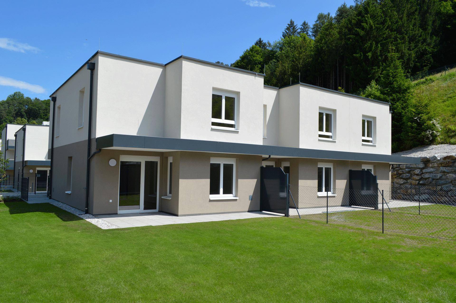 Rückseite des Gebäudes mit Terrassen und privaten Gärten, umgeben von Natur.