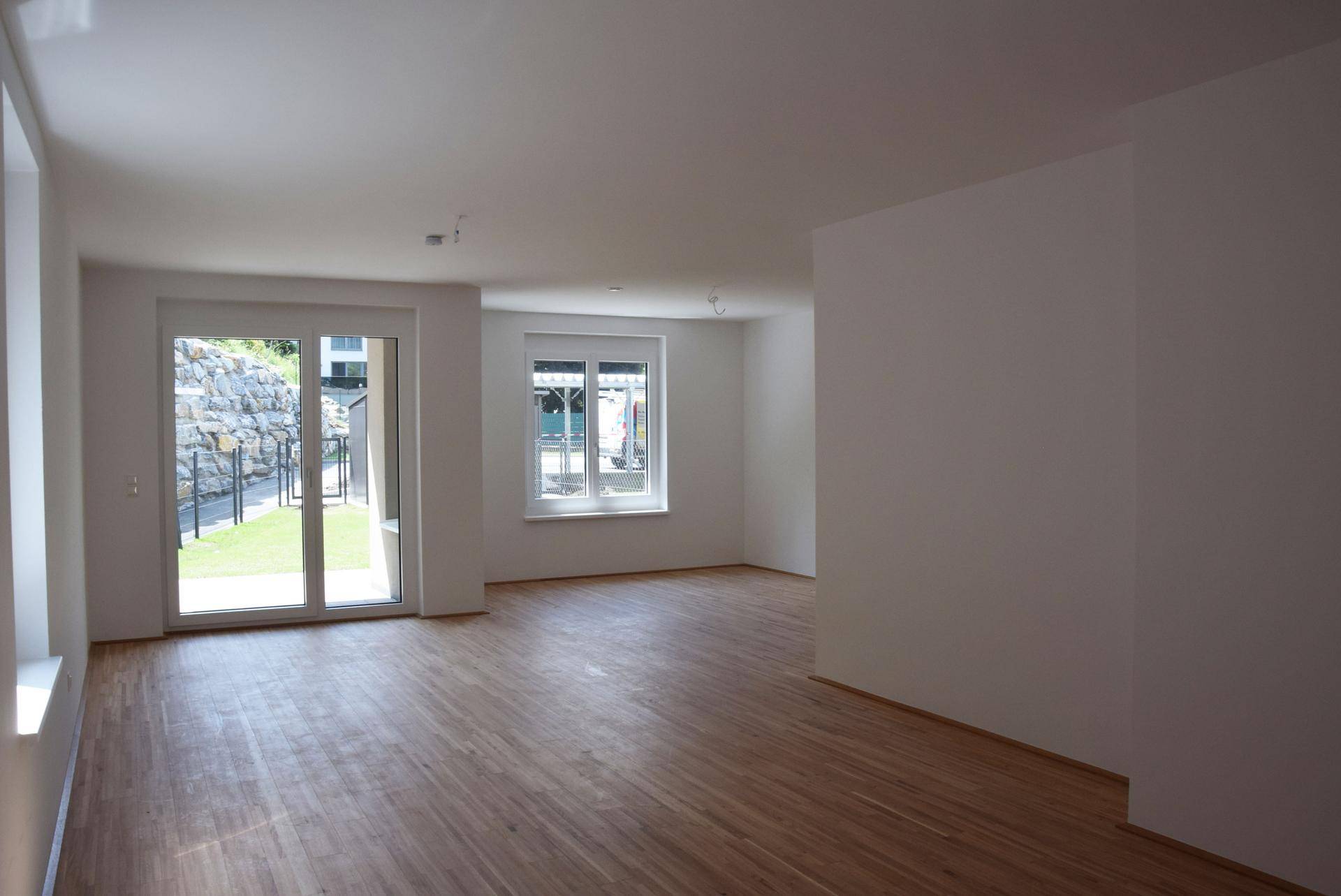 Geräumiges, helles Wohnzimmer mit Holzboden und großen Fenstern mit Zugang zum Garten.