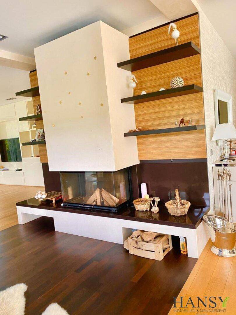 Moderner Kamin als Raumteiler mit Holzverkleidung und dunklem Holzboden im Wohnbereich.