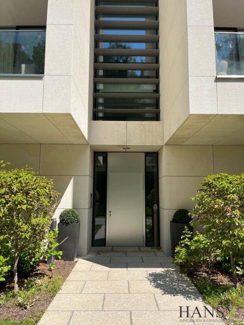 Moderner Eingangsbereich mit klaren Linien und gepflegter Bepflanzung, passend zur Architektur.