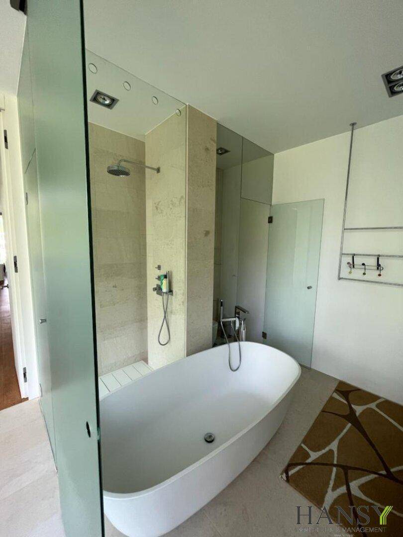 Modernes Badezimmer mit freistehender Badewanne und begehbarer Dusche, hell gefliest.
