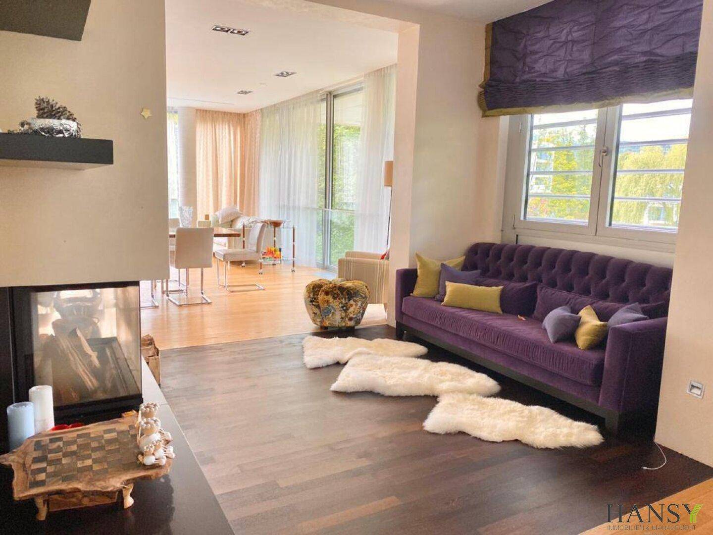 Gemütlicher Wohnbereich mit dunklem Holzboden, lila Sofa und Blick auf den Essbereich.