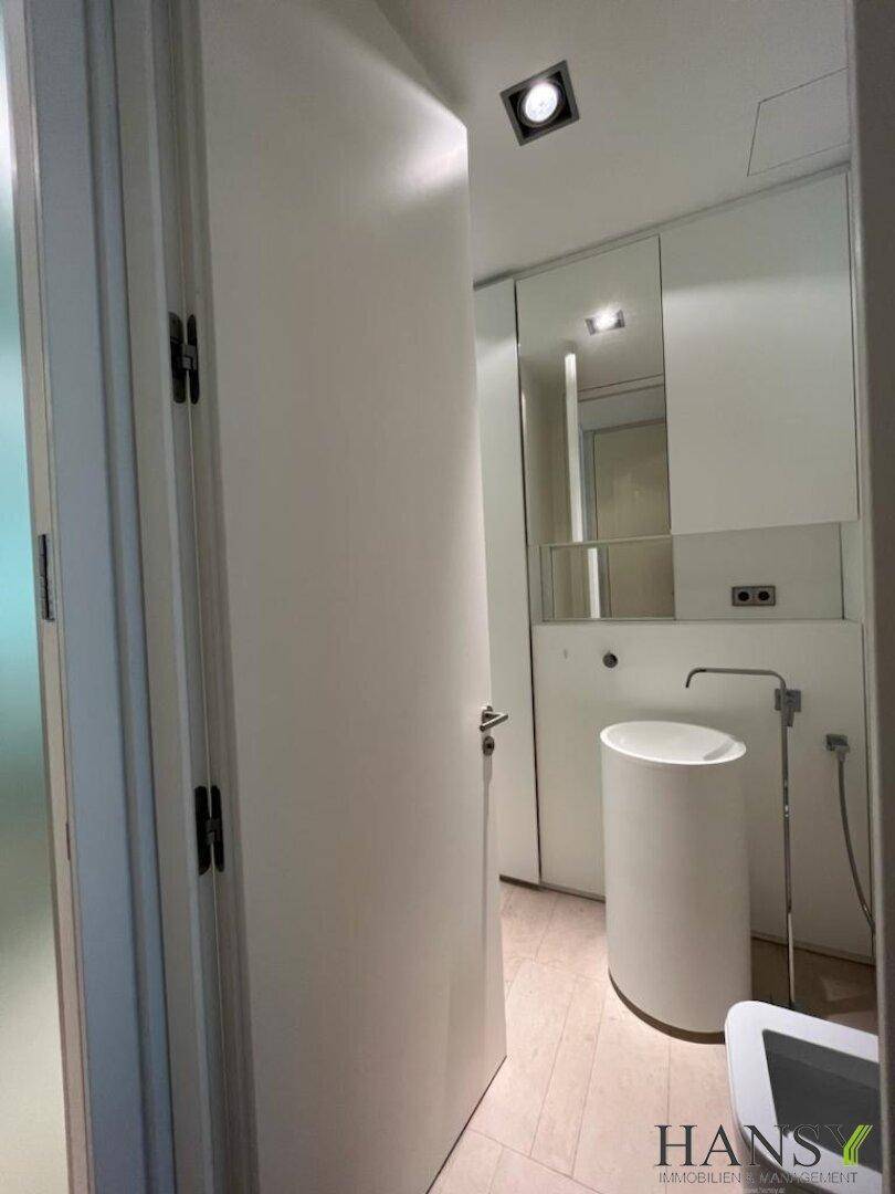 Modernes Gäste-WC mit minimalistischem Design, weißem Standwaschbecken und Spiegelschrank.