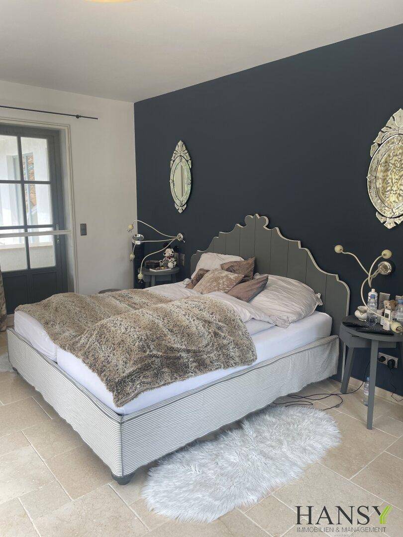Gemütliches Schlafzimmer mit dunkler Akzentwand, großem Bett und Zugang zum Außenbereich.