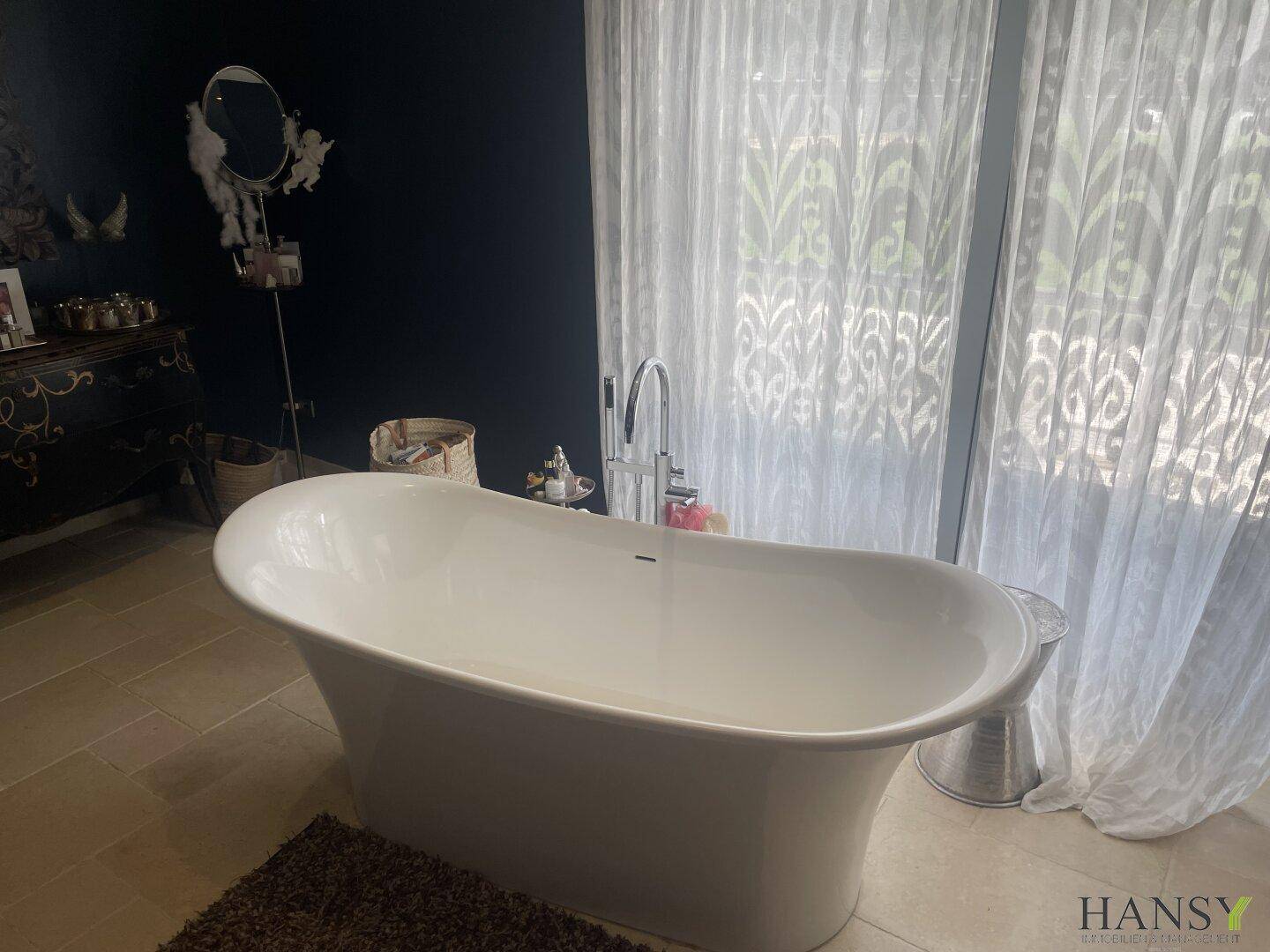 Elegantes Badezimmer mit freistehender Badewanne und großen Fenstern für viel Tageslicht.