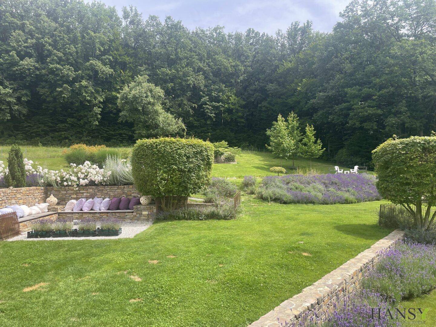 Gepflegter Garten mit weitläufigen Rasenflächen, Lavendelbeeten und altem Baumbestand.