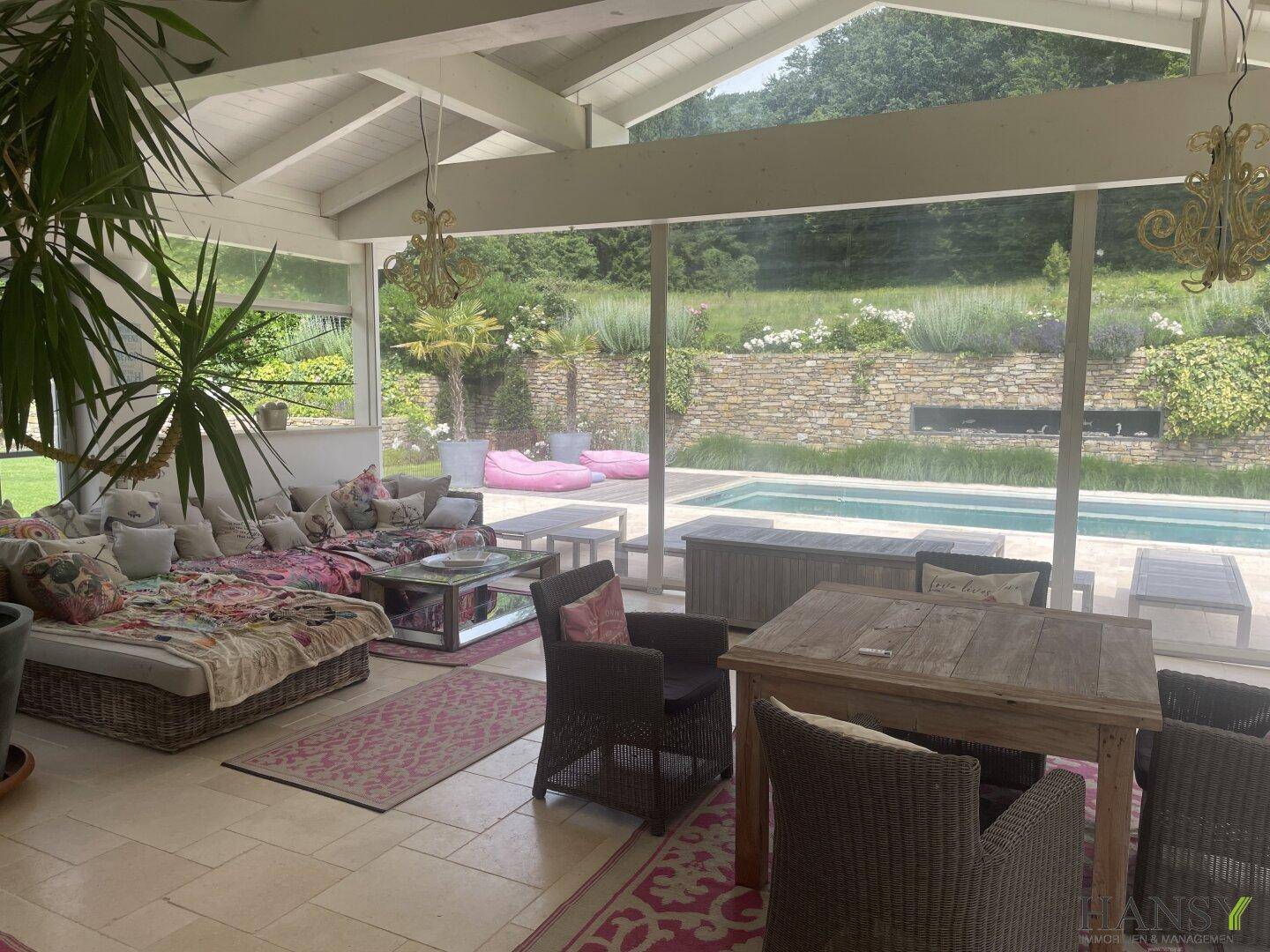 Heller Wintergarten mit Blick auf den Pool und den Garten, ideal zum Entspannen.