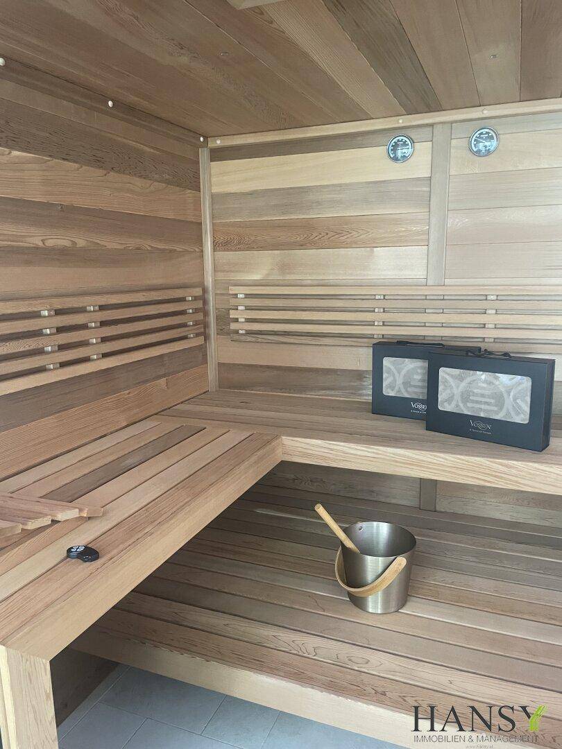 Moderne Holzsauna mit Bänken und traditionellem Saunaeimer, bereit zur Nutzung.