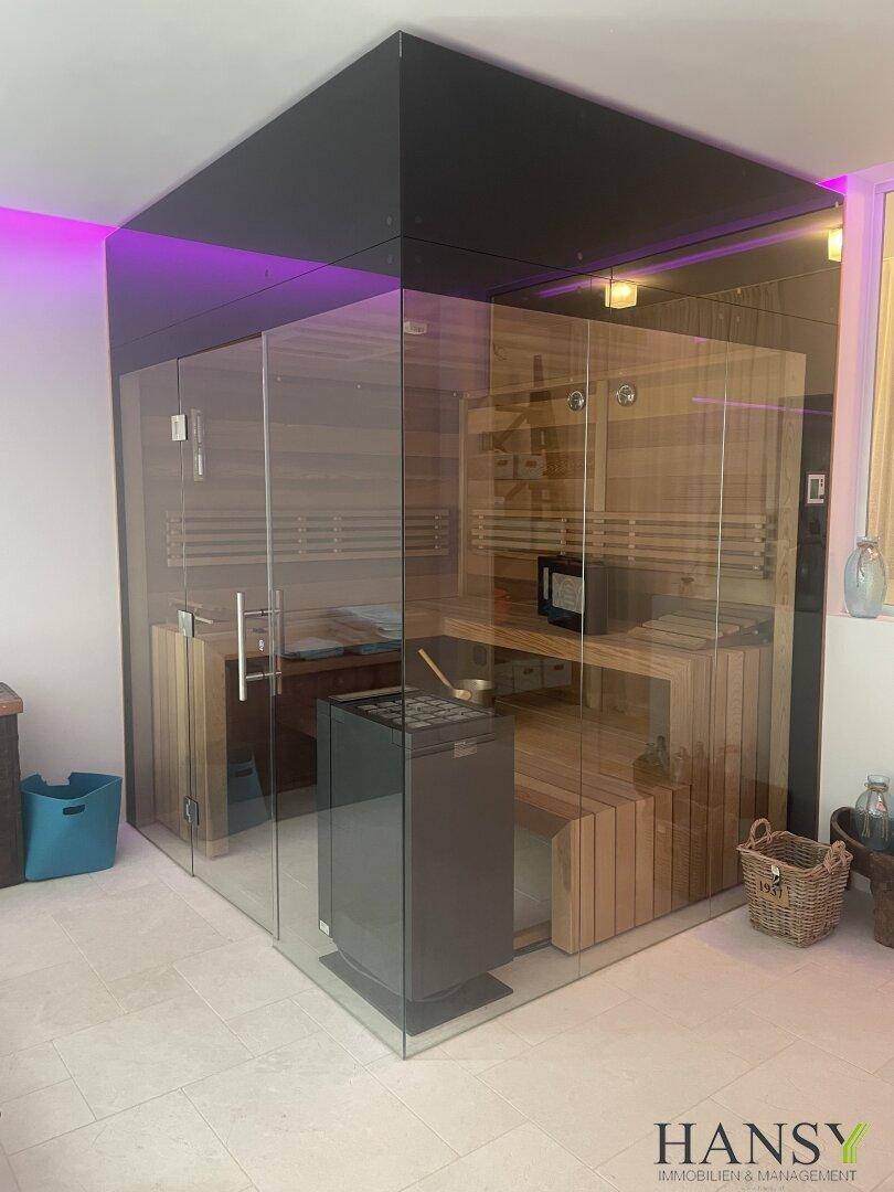 Exklusive Sauna mit Glasfront und stimmungsvoller Beleuchtung als Teil des Wellnessbereichs.