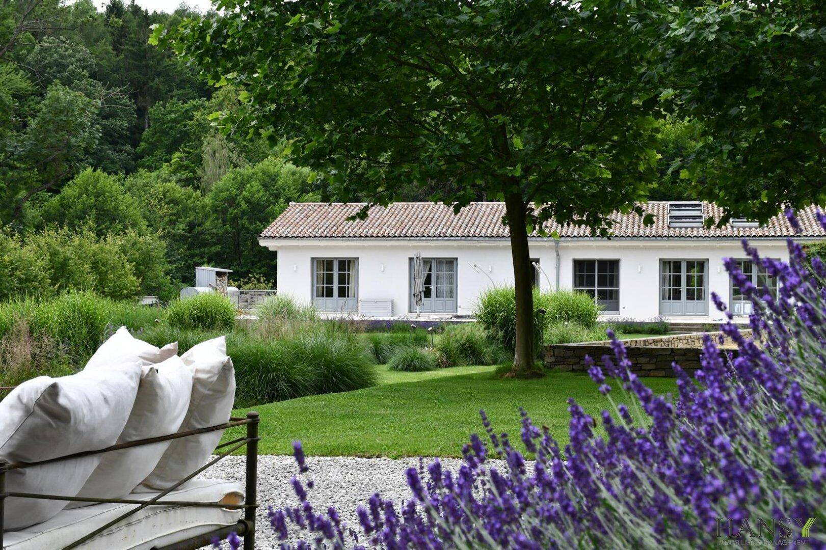 Blick auf das Landhaus vom blühenden Garten aus, umgeben von Lavendel und grünen Pflanzen.