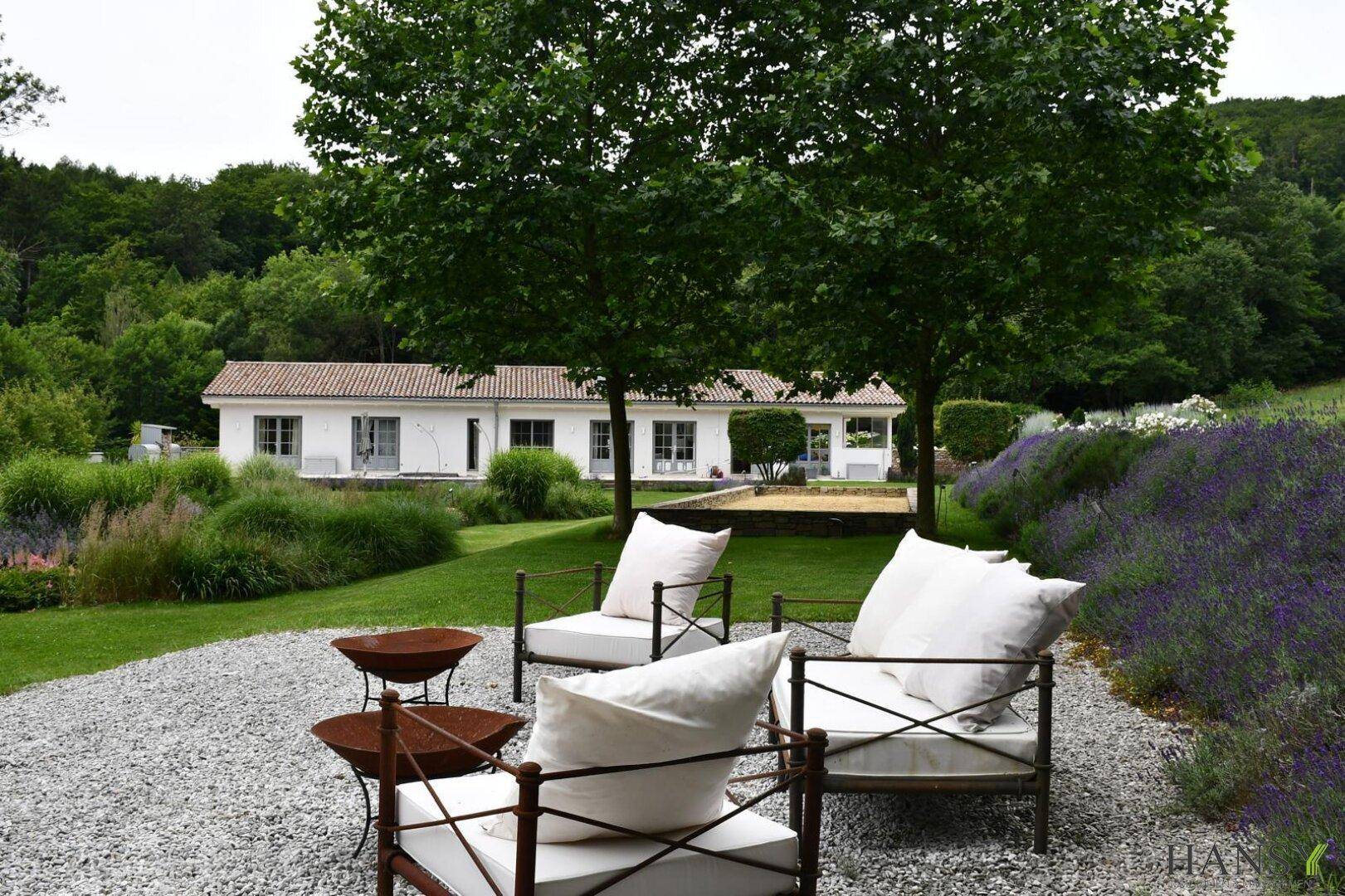 Weitläufiger Gartenbereich mit Sitzgelegenheiten, Kiesfläche und Blick auf das Haupthaus.