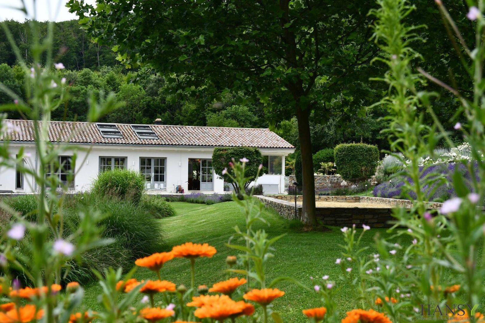 Idyllisches Anwesen mit gepflegtem Garten, blühenden Pflanzen und weitem Blick in die Natur.
