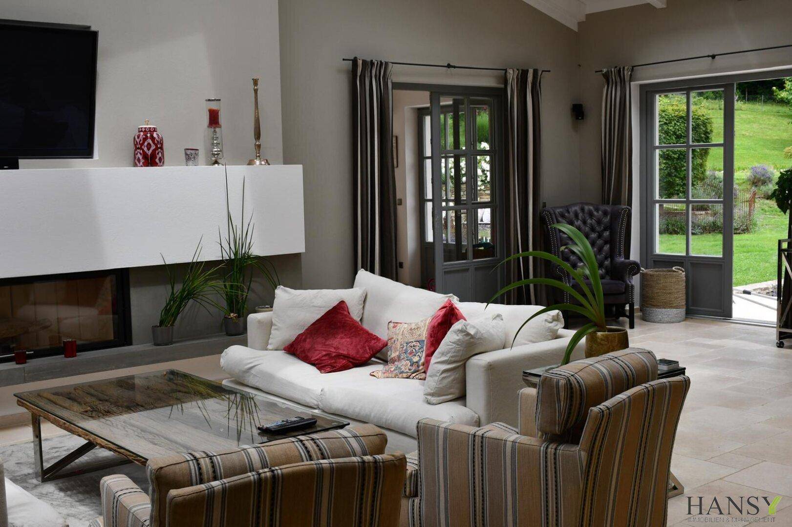 Gemütliches Wohnzimmer mit Kamin, bequemen Sofas und Zugang zum Garten.