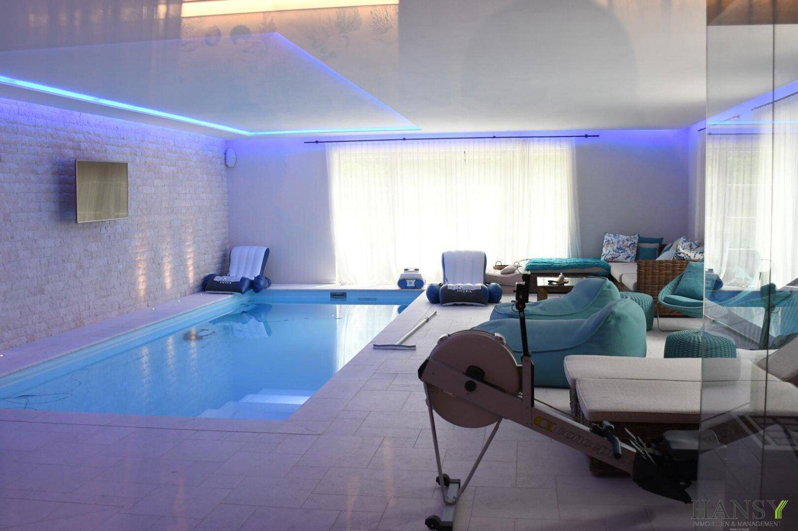 Geräumiger Innenpoolbereich mit Fitnessgeräten und Lounge-Möbeln, ideal für Sport und Entspannung.