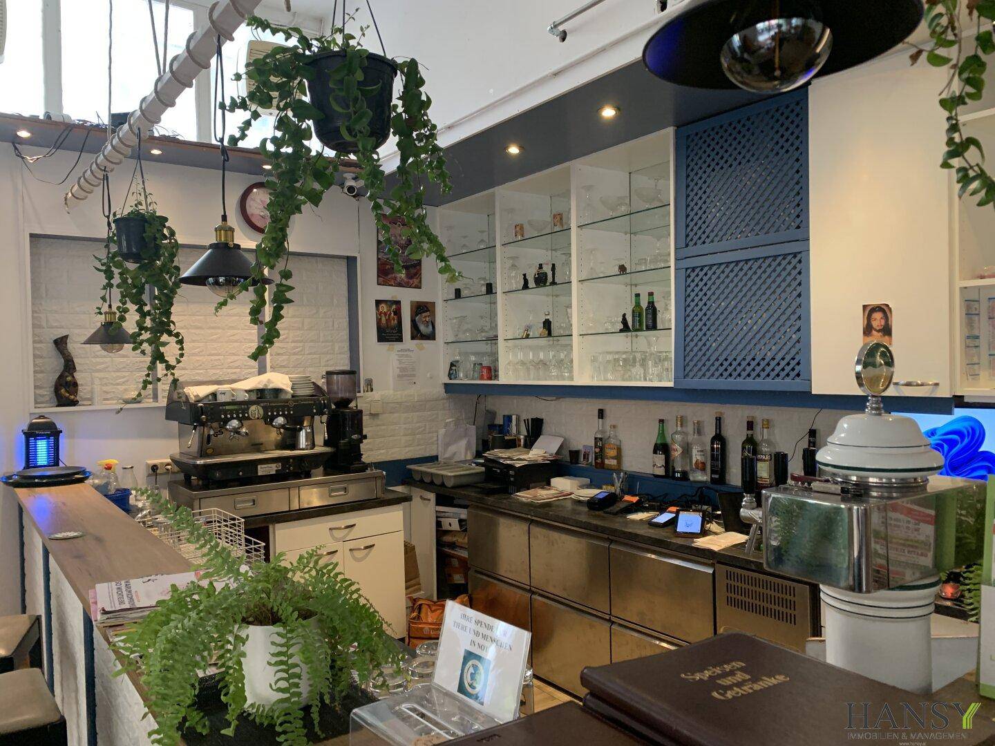 Thekenbereich mit Kaffeemaschine, Regalen und Getränkeauslage in einem Gastronomiebetrieb.