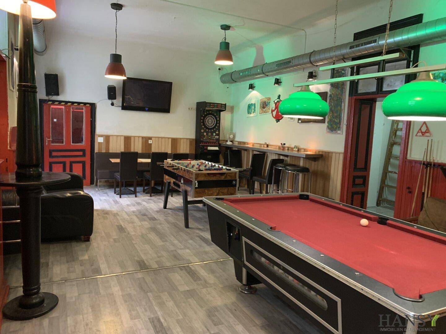 Großer Freizeitraum mit Billardtisch, Kicker, Dartscheibe und verschiedenen Sitzgelegenheiten.