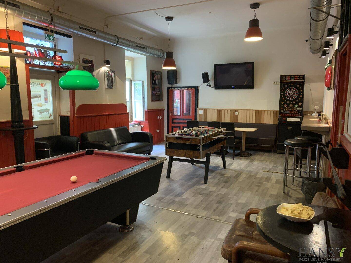 Übersicht des Freizeitbereichs mit Billard, Kicker, Dart und einer kleinen Bar im Hintergrund.