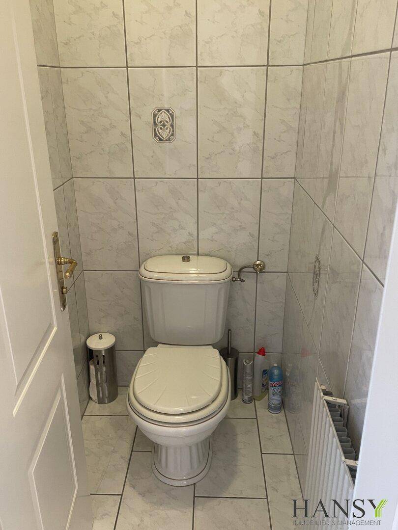 Kleines WC mit hellen Fliesen an Wänden und Boden.