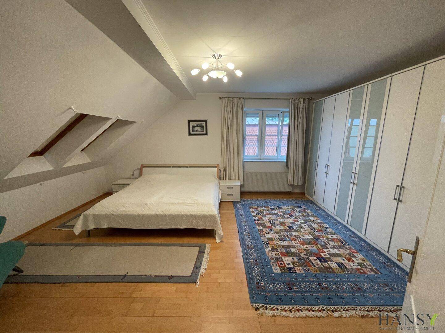 Geräumiges Schlafzimmer mit Doppelbett, großem Kleiderschrank und Dachschrägen.
